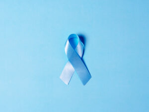 Top view on Blue satin Ribbon symbol of prostate cancer awareness on a bright blue background. Concept of medicine and health care