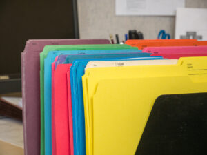 Close-up cropped image of pen and files with keyboard and spectacles on wooden office desk